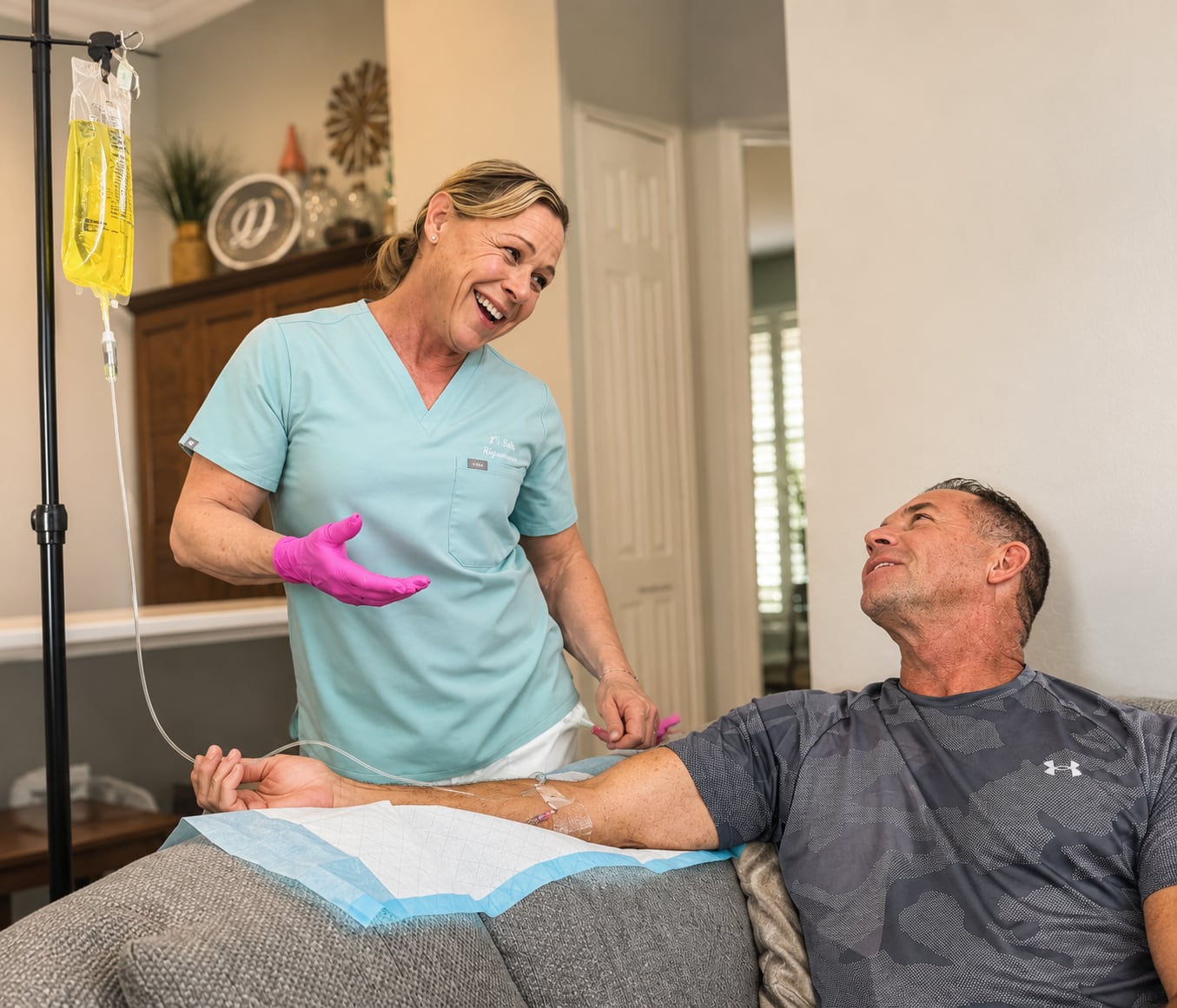 Sara, a registered nurse, smiling while administering a mobile IV therapy session to a client